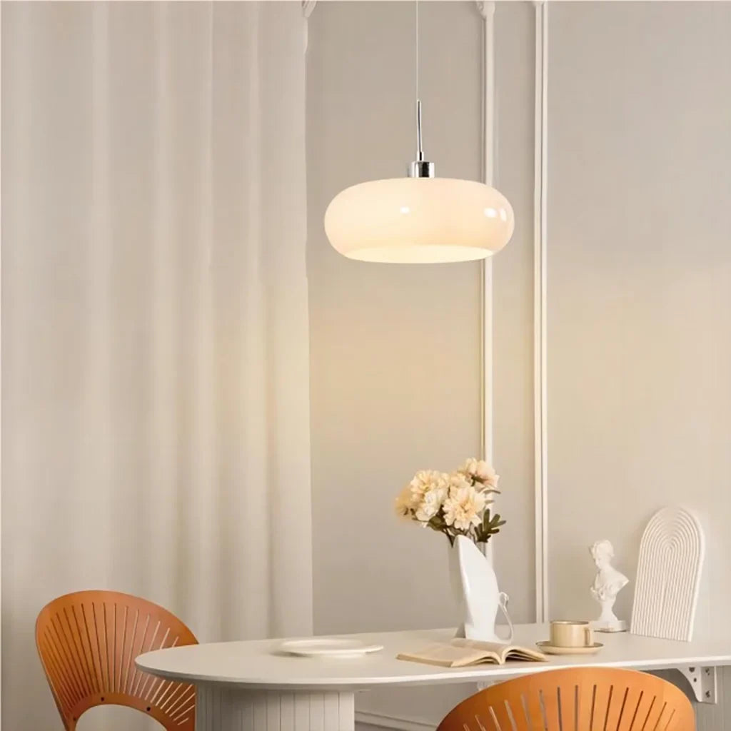 White glass pendant light over a glass side table beside seascape wall art