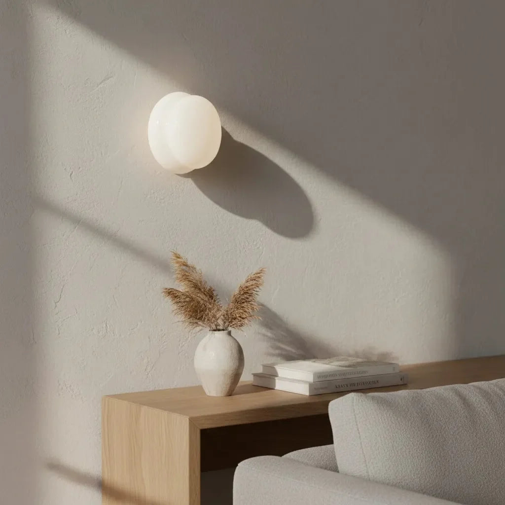 White globe glass wall sconce casting soft shadow on plaster wall