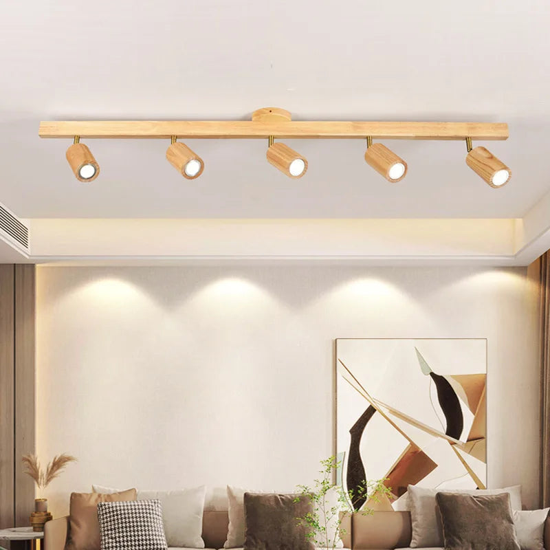 Oak track bar lighting a warm living room above a sofa with cushions