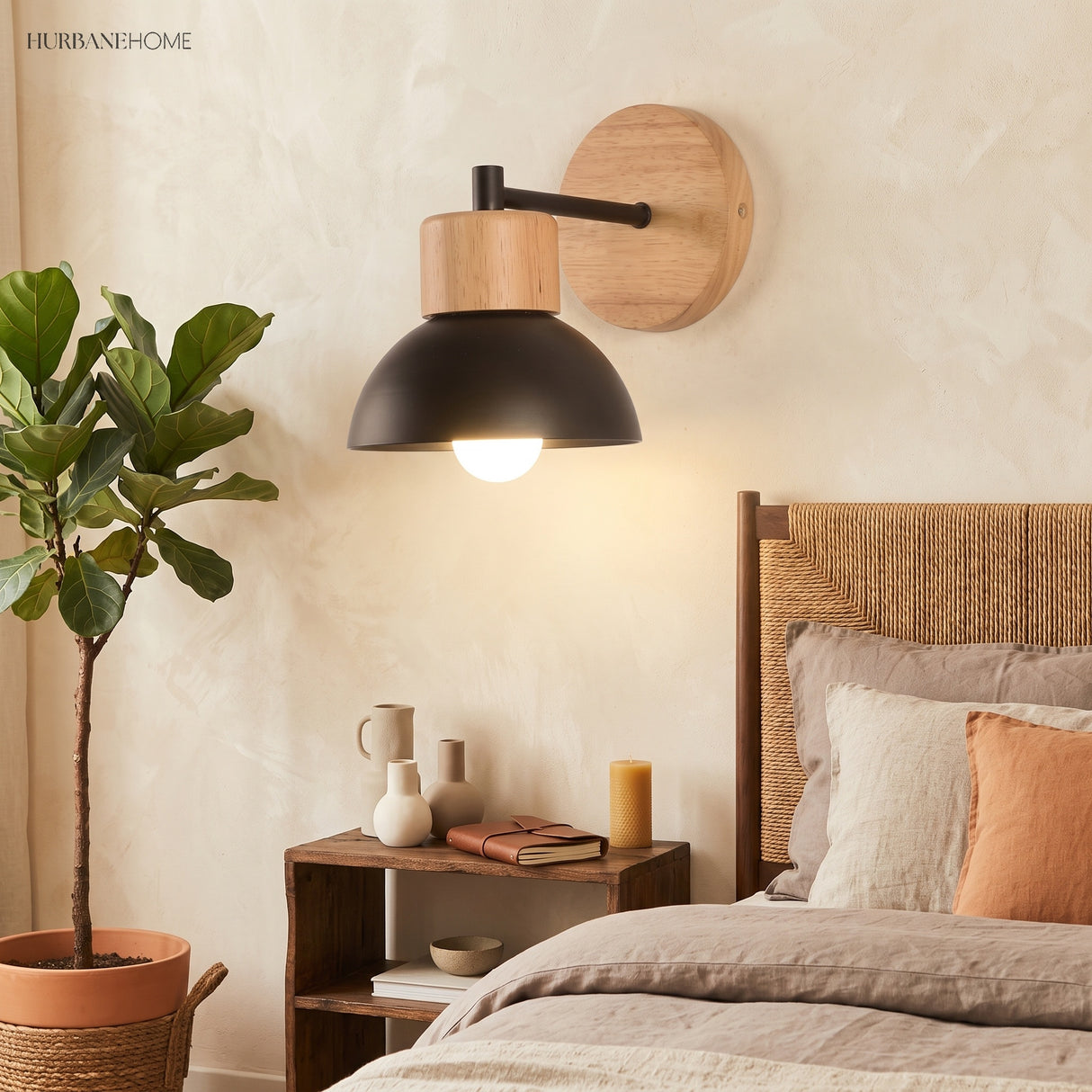 Wood sconce with a black dome lit beside a bed and potted plant