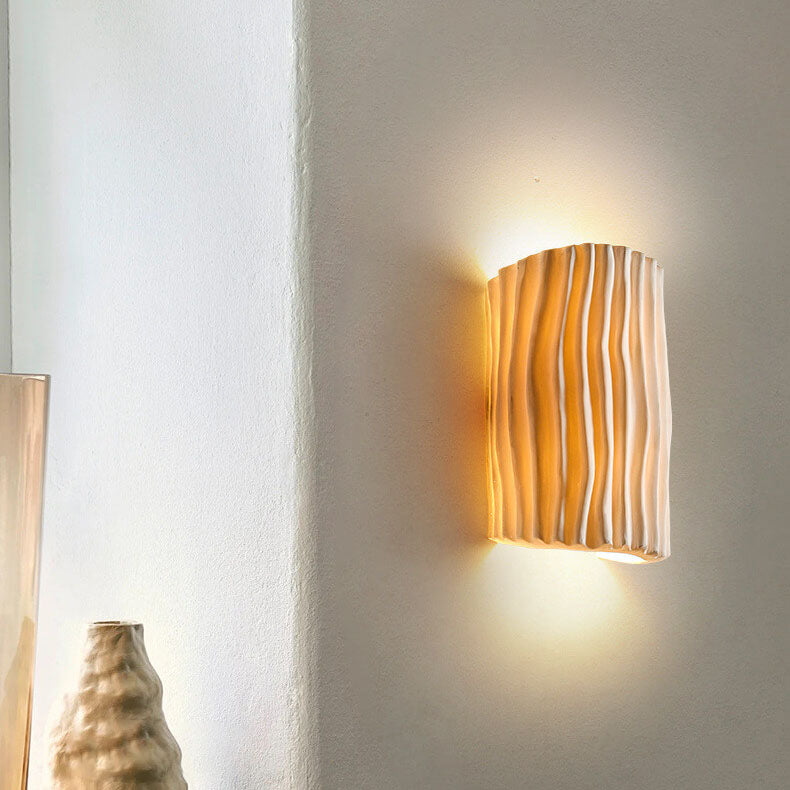 Cream resin wall sconce with rippled shade casting warm ambient light