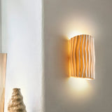 Cream resin wall sconce with rippled shade casting warm ambient light