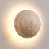 Warm honey-toned travertine LED wall sconce lit against a plain white wall