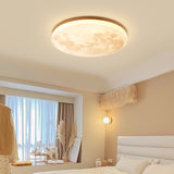 Moon round LED flush mount ceiling light glowing softly in a bedroom