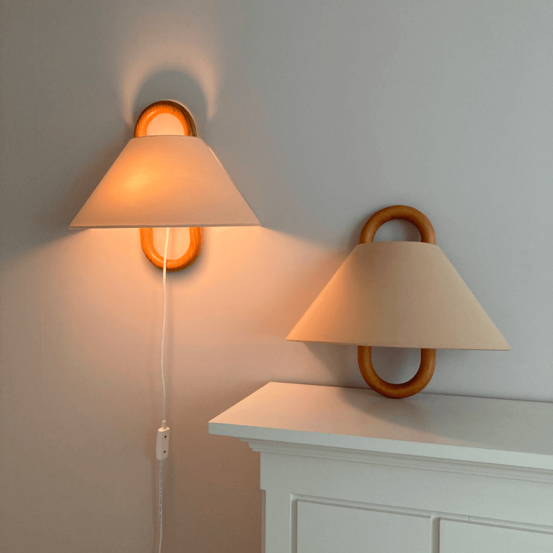 Pleated fabric wall sconce shown against a plain studio background