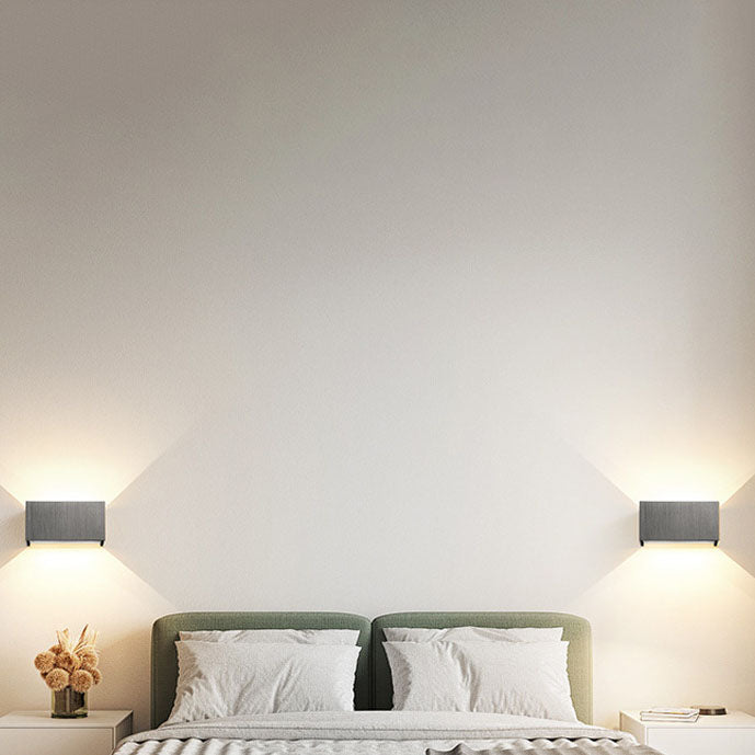Gold wall sconce shown against a plain wall in warm light