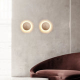 Pair of stone wall sconces on a grey wall above a burgundy velvet sofa