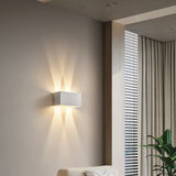 White rectangular LED sconce throwing warm beams up and down a wall