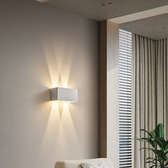 White rectangular LED sconce throwing warm beams up and down a wall