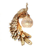 Gold peacock wall sconce with colourful jewelled feather eye-spots on white