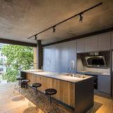 Black spotlights grazing a showroom partition wall with warm pools of light