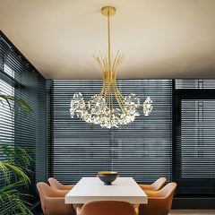 Gold dandelion chandelier over a dining table beside slatted window blinds