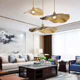 Single gold lotus leaf pendant light on a black studio background