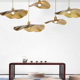 Warm gold lotus leaf pendant lights glowing above a lakeside dining space