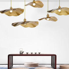 Warm gold lotus leaf pendant lights glowing above a lakeside dining space