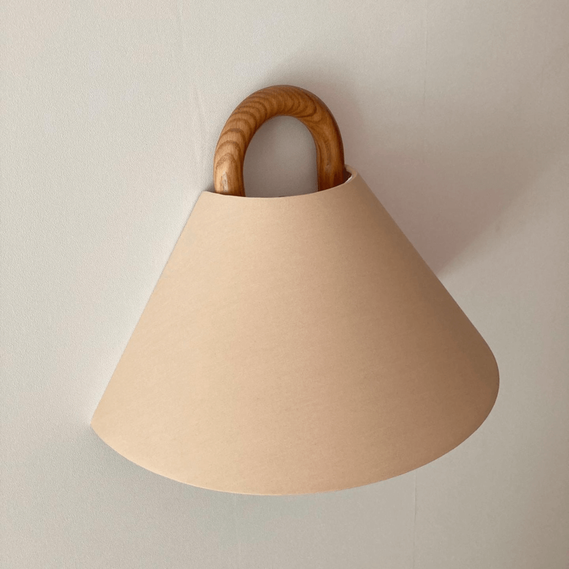 Fabric wall sconce shown unlit on a plain wall
