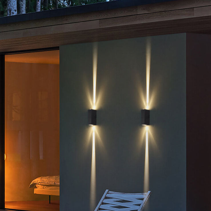 Two black up and down wall lights beside a glass wall and bedroom at dusk