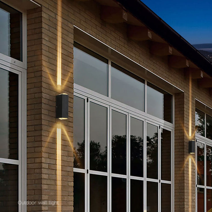Rectangular wall light casting warm beams on a brick building at twilight