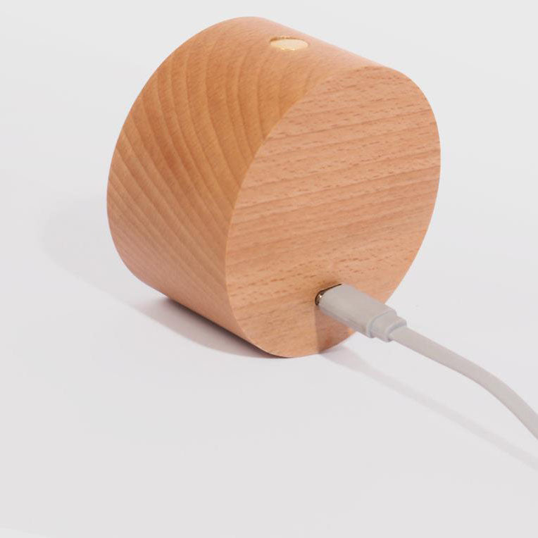 Wooden wall sconce charging over a USB cable on a surface