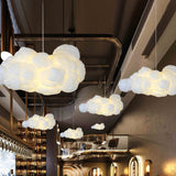 Row of white cloud pendant lights lit over an industrial pipe-ceiling bar