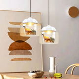 Pair of white-capped glass pendants with tiger and antelope figures over a dining area