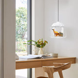 Clear glass pendant with white cap and safari figures hanging beside a sunlit desk window
