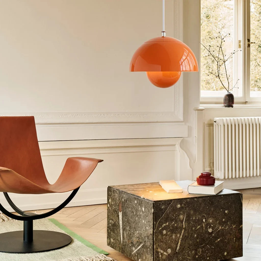 Orange bud metal pendant light glowing warmly above a styled table