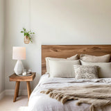 White ceramic bedside table lamp on a timber nightstand next to a bed