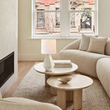 White ceramic table lamp on nesting travertine coffee tables in a living room