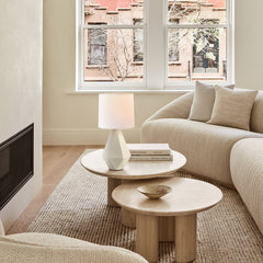 White ceramic table lamp on nesting travertine coffee tables in a living room