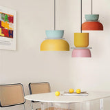Three colorful pendant lights above a dining setting