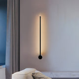 Slim vertical black wall sconce on a beige bedroom wall