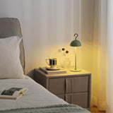 Green rechargeable dome lamp glowing on a bedside cabinet next to a made bed