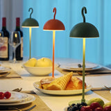 Green, orange and red dome lamps lit across a set dinner table with fruit