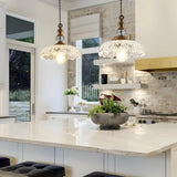 Transparent glass flower pendant light with brass fitting on a light background