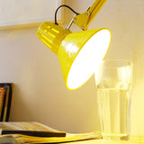 Yellow swing arm floor lamp standing upright on a studio floor