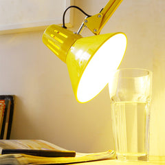 Yellow swing arm floor lamp standing upright on a studio floor