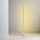 White corner floor lamp glowing against a soft warm wall in an empty room