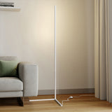 White floor lamp on a triangle base with foot switch cord near a grey sofa