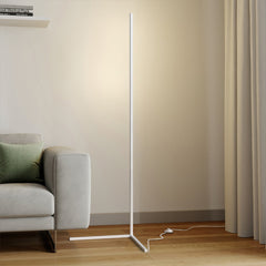 White floor lamp on a triangle base with foot switch cord near a grey sofa