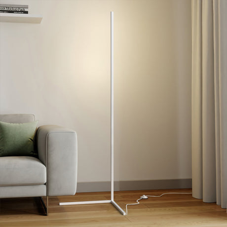 White floor lamp on a triangle base with foot switch cord near a grey sofa