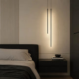 Black tube pendant light close-up against a plain wall