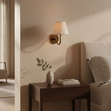 Rustic pleated fabric wall sconce with curved metal arm and round backplate, mustard yellow shade styled shot 16