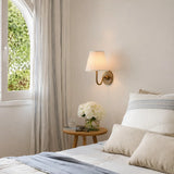 Single-head wall sconce with tapered pleated fabric shade and warm bulb glow, dusty blue shade angled view 3
