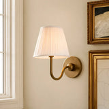 Pleated linen shade wall sconce shown against a plain studio background, sage green shade side view 2