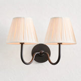 Detail of the round backplate and curved arm on the pleated fabric sconce, dusty blue shade product shot 27