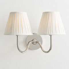 Chrome-finish wall sconce with pleated linen shade and slim curved arm, white shade lit shot 25