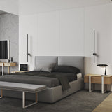 Two vertical black wall lights flanking a grey upholstered bed