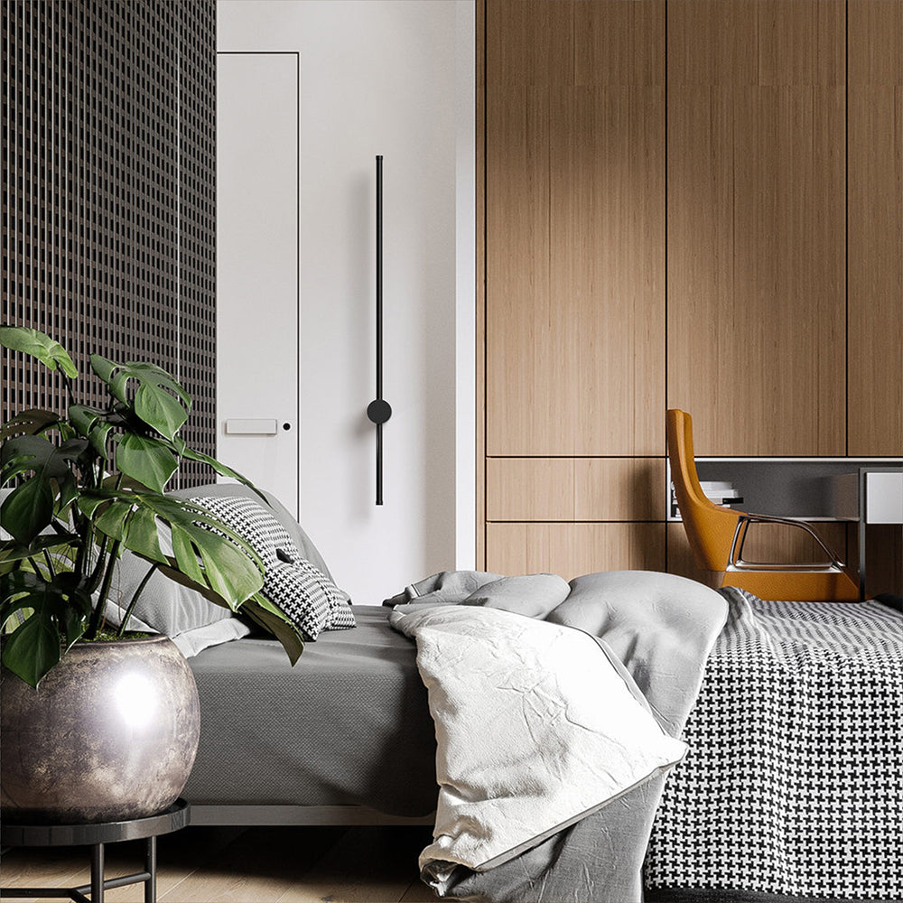 Vertical black wall light beside a wardrobe with a leafy plant