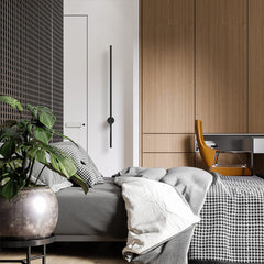 Vertical black wall light beside a wardrobe with a leafy plant